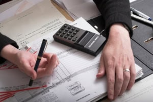 Bild von Martin Baumann auf Pixabay Datailaufnahme von zwei Händen auf Akten und einem Taschenrechner.