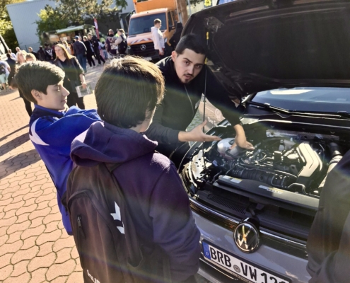 Berufemarkt2026_AutohausMothor Zwei Jugendliche lassen sich von Autohaus Mothor den Motorraum eines Autos auf dem 26. Berufemarkt Westbrandenburg zeigen