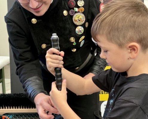 Berufemarkt2026_Schornsteinfeger Ein Schornsteinfeger baut mit einem Jungen einen Mini-Besen